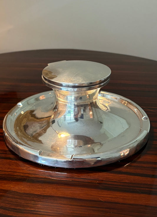 Silver inkwell on a wooden surface